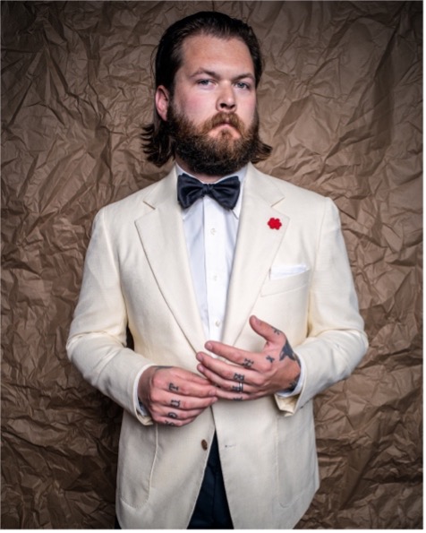 Young bearded man wearing white tuxedo and black bow tie designed by HKT of Atlanta.
